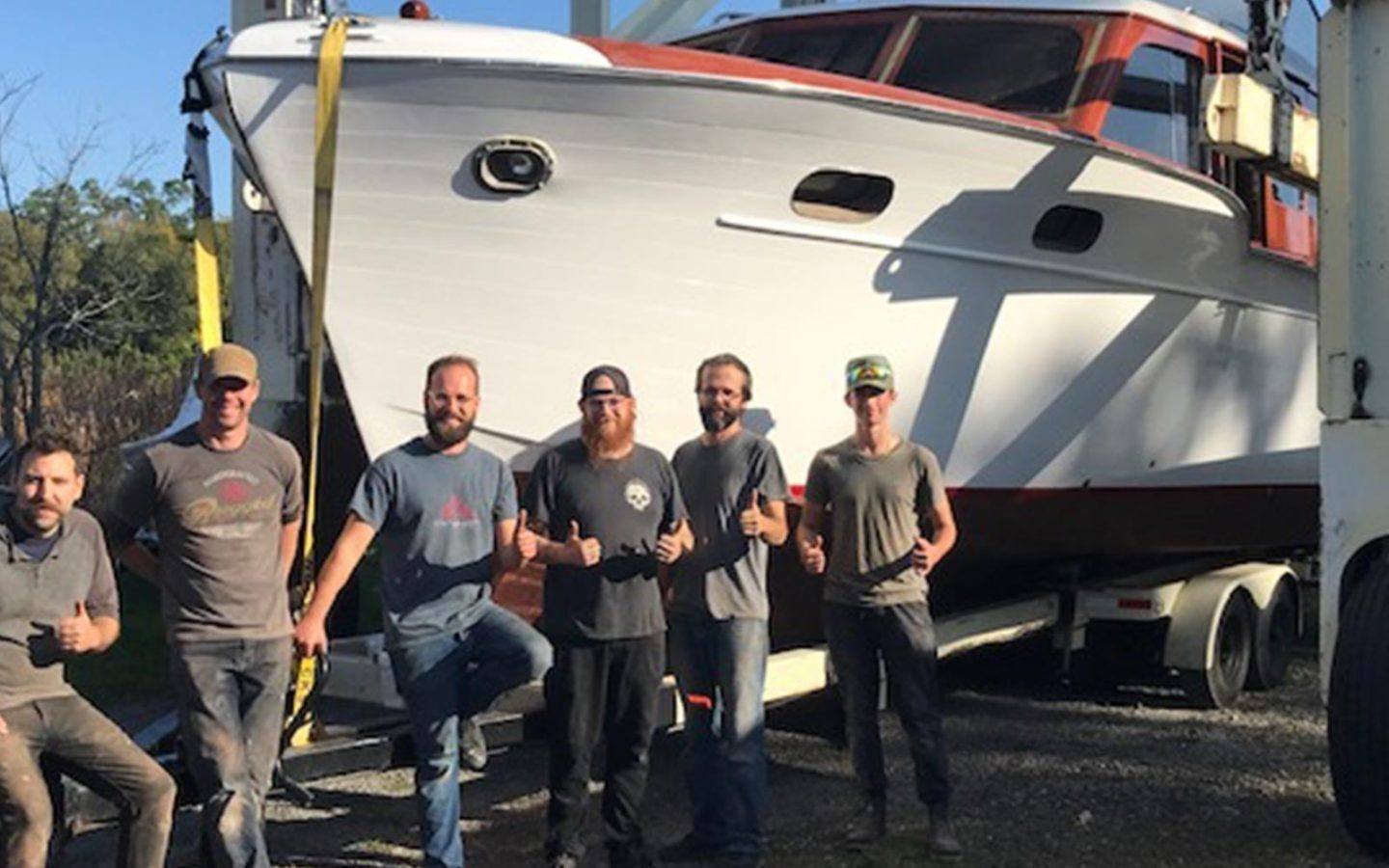 six MHShips&Equipment employees standing in front of a large boat