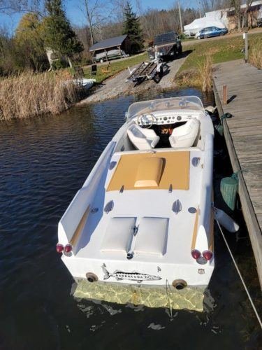 Arena Craft boat with cushioned seats tied to a dock in the water