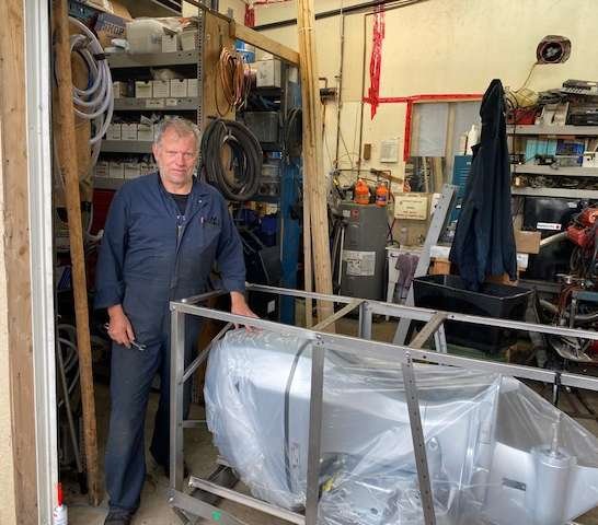 a man standing next to a metal object in a garage