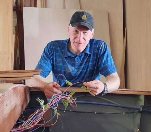 a man in a blue shirt and cap working on a piece of wood